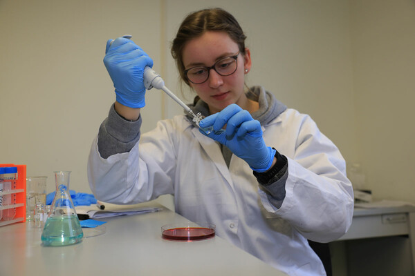 Eine Freiwillige in einem weißen Kittel testet etwas im Labor.