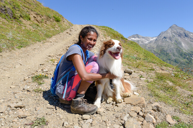 Shalina und ihr Hund Linus am Rande eines Wanderweges auf einem Berg.